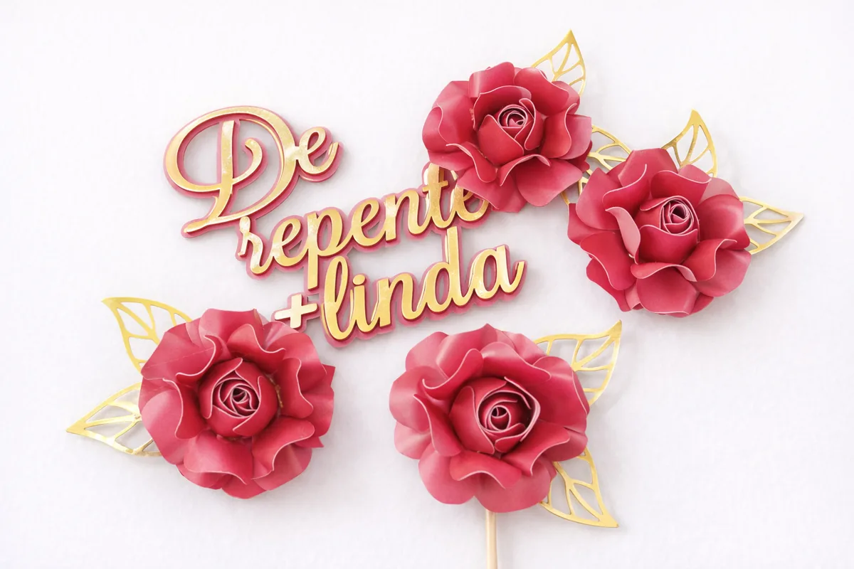 Rosas de papel bordô com folhas douradas e a frase De repente mais linda recortada em dourado